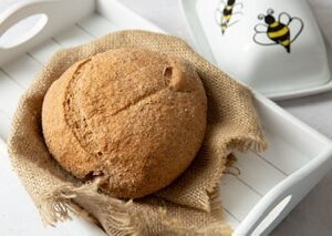 Wholemeal loaf on hessian, white tray and butter dish