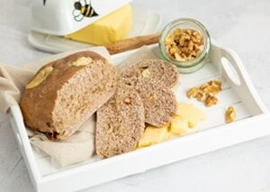 Cheese and walnut loaf, sliced on white tray with cheese, walnuts also butter dish with butter and wooden knife