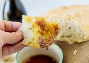 Piece of ciabatta in a hand after dipping in olive oil and balsamic